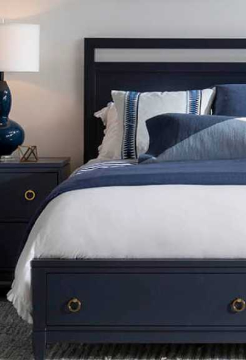 Coastal styled bedroom with navy blue bed frame underneath a white bed with navy blue pillows on top