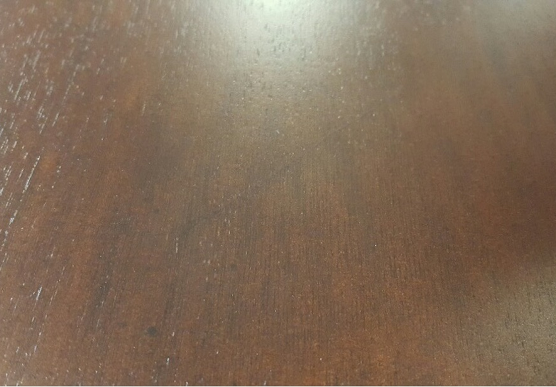 A close-up of a wooden surface with a smooth texture and dark brown finish. 