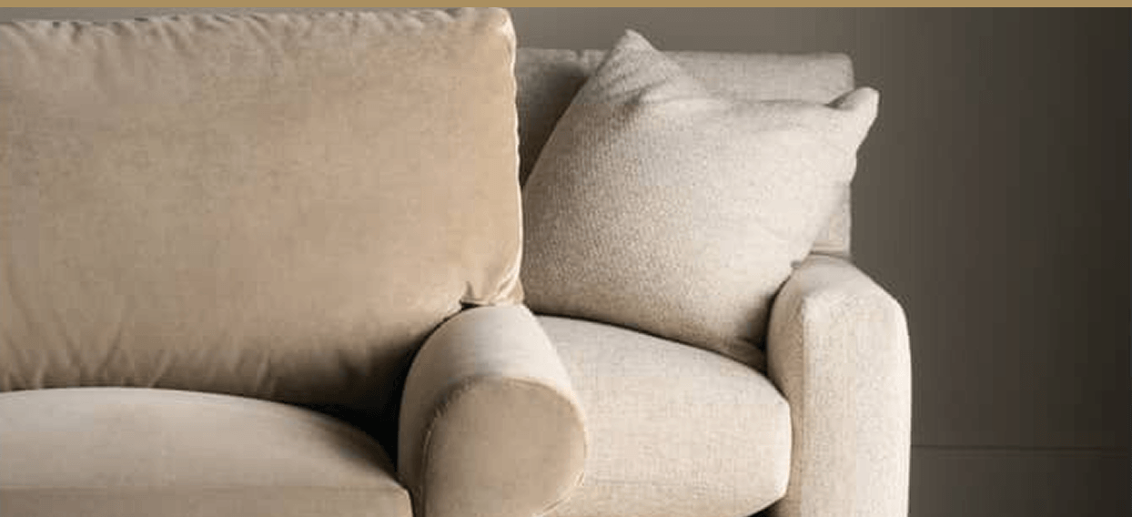 Close-up of a beige upholstered sofa with soft, 
            textured cushions and rounded armrests, creating a warm, comfortable, neutral-toned living room feel.