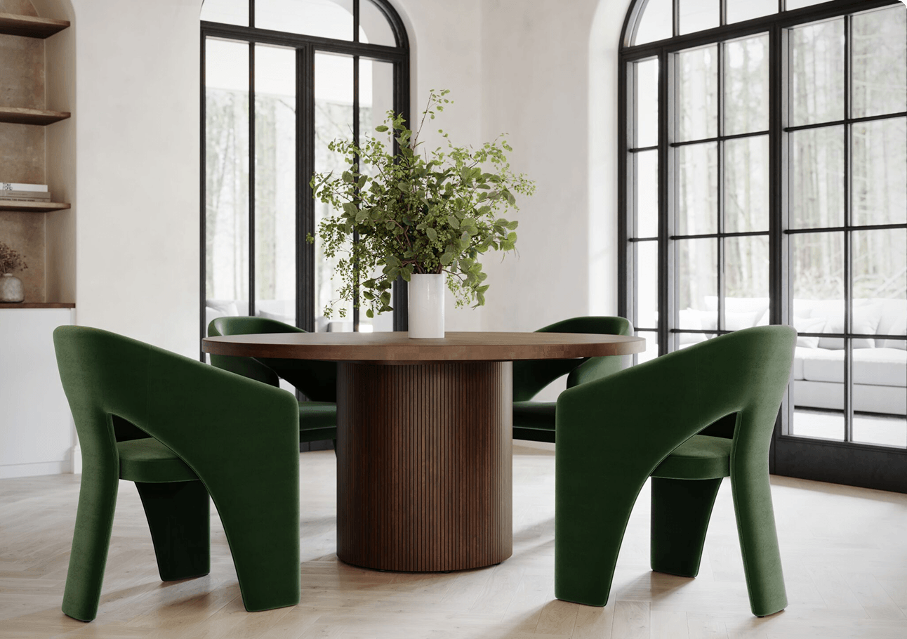 A serene modern dining room features a round wooden table, sculptural green chairs, leafy branches, and tall arched black windows;