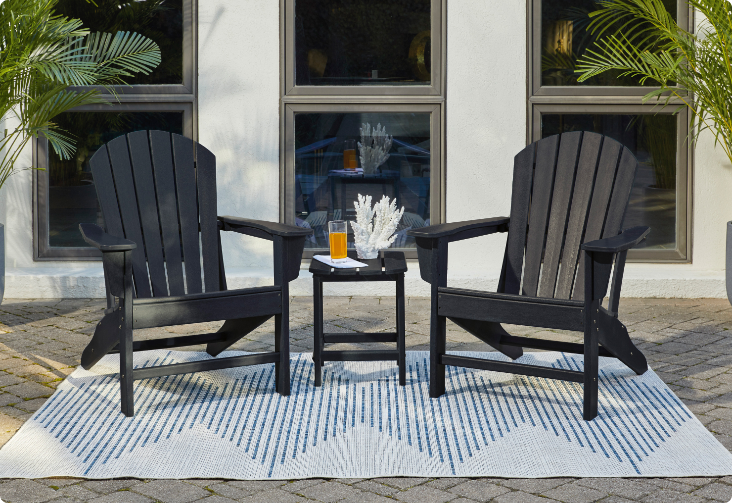 An all black outdoor furniture set with Adirondack chairs, creating a welcoming outdoor space.
