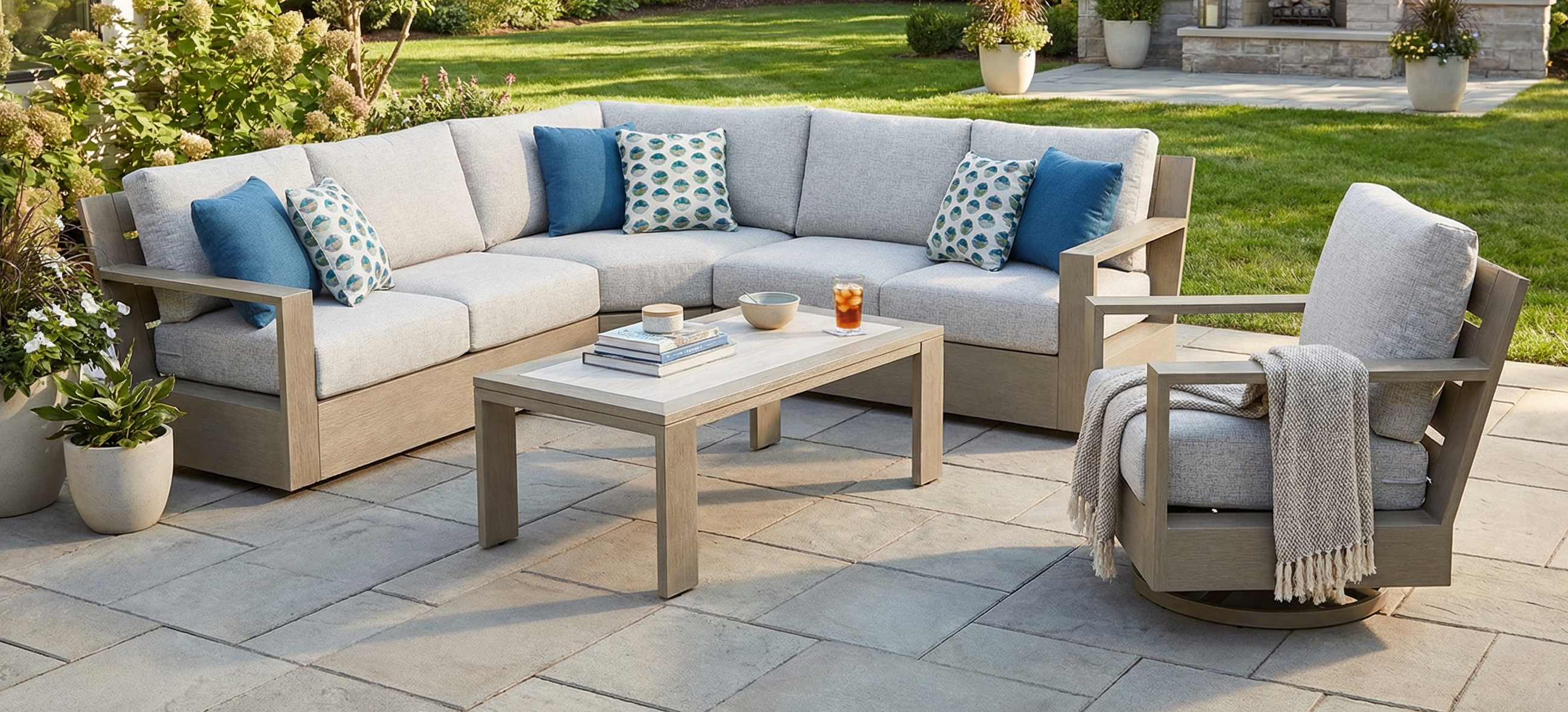 Outdoor Agio Cove dining set with a marble top table and six gray cushioned chairs, overlooking a scenic coastal view.