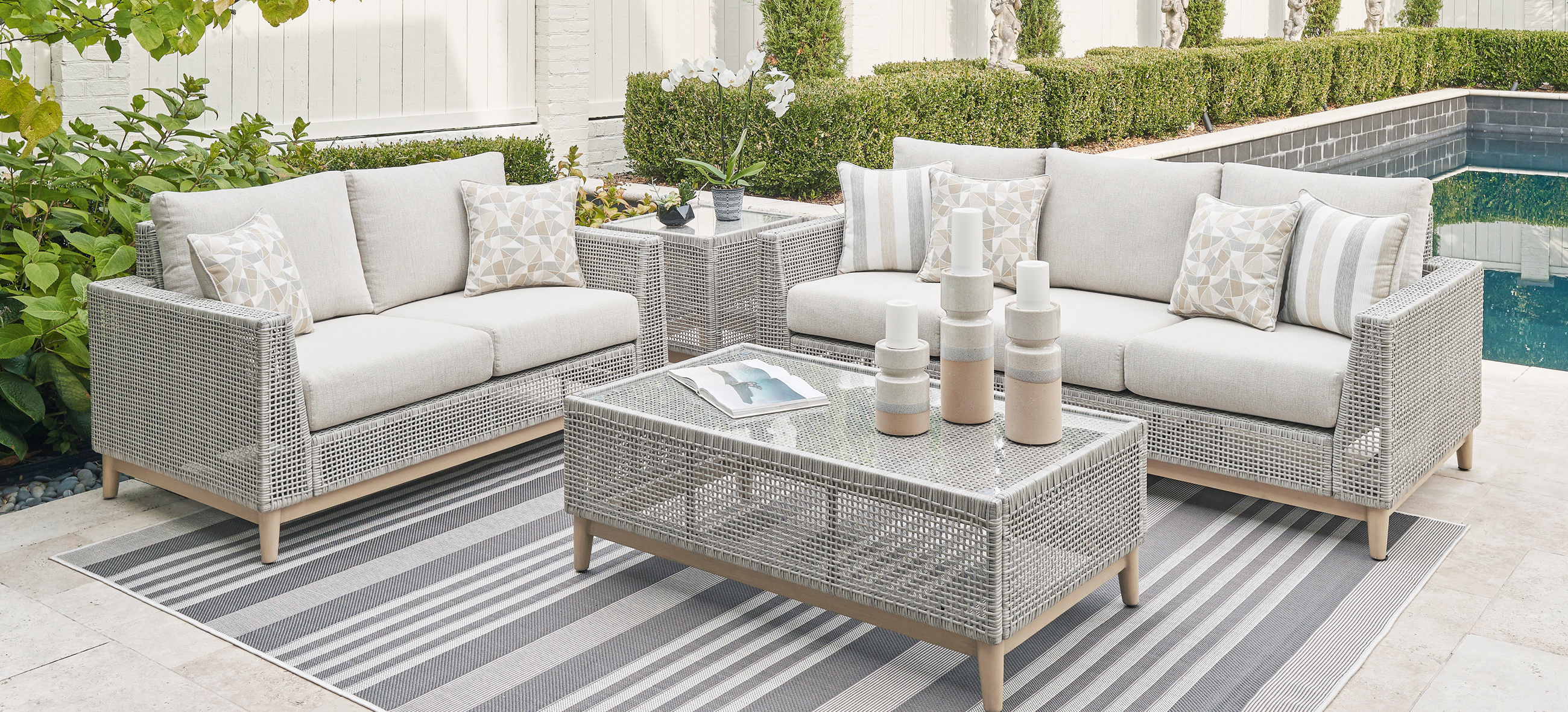 Outdoor Agio Cove dining set with a marble top table and six gray cushioned chairs, overlooking a scenic coastal view.