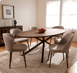 Sunlit dining room with a round wooden table, bowl of red apples, and four upholstered chairs on a pale rug; bright, calm, and inviting.