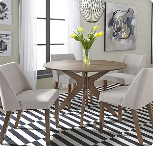 A bright, modern dining room with a round wood table, four pale upholstered chairs, yellow flowers, abstract art, and a bold striped rug.