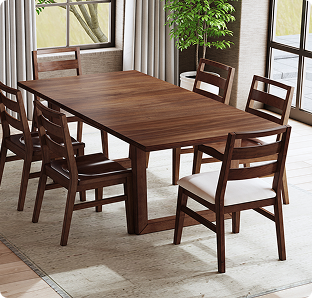 A dark wood dining table with matching chairs sits in a bright room beside tall windows, pale curtains, and a leafy plant, creating a warm, inviting feel.